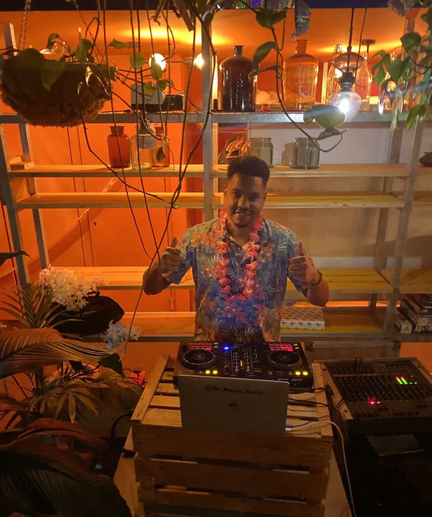 DJ Manoss behind the DJ booth at a party