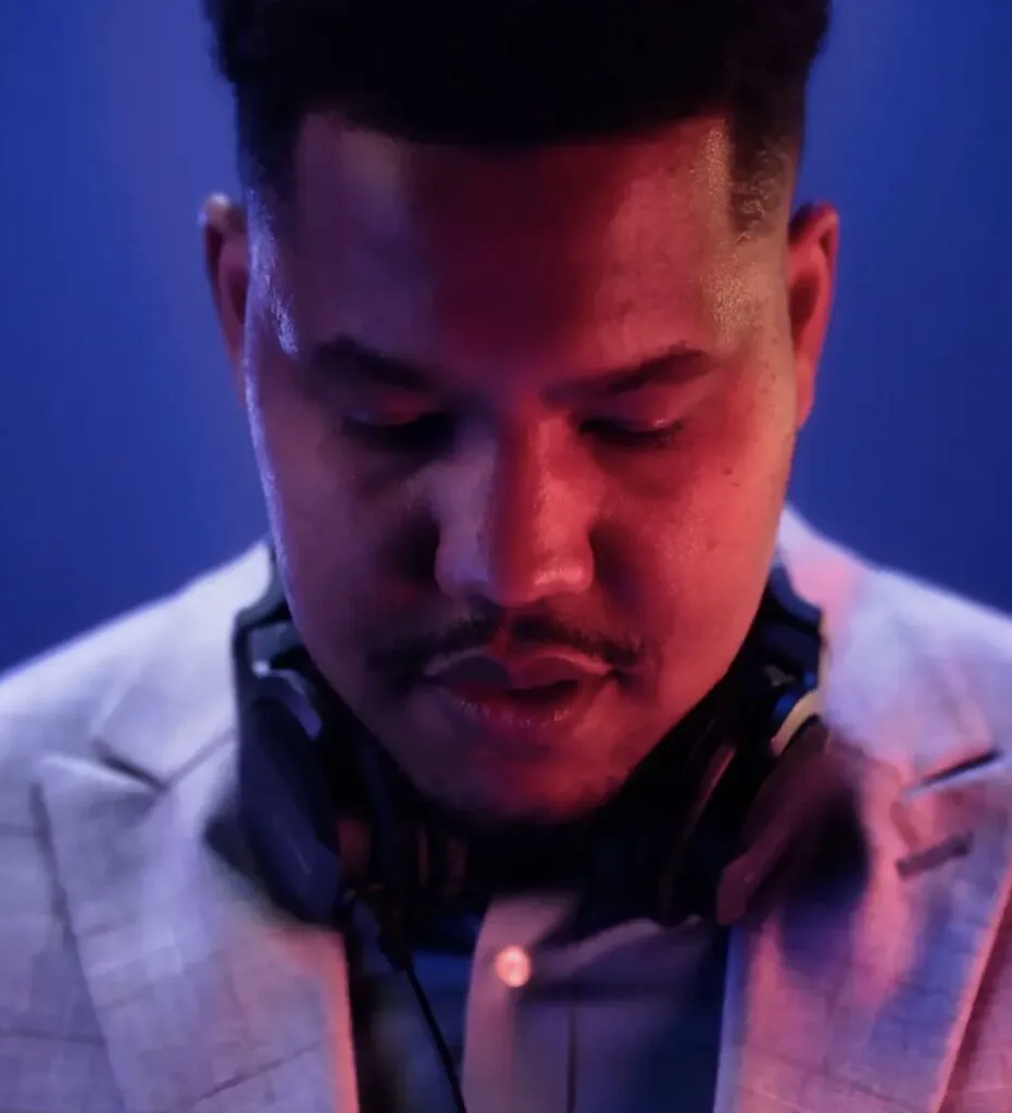 DJ Manoss with headphones under blue and magenta club lighting